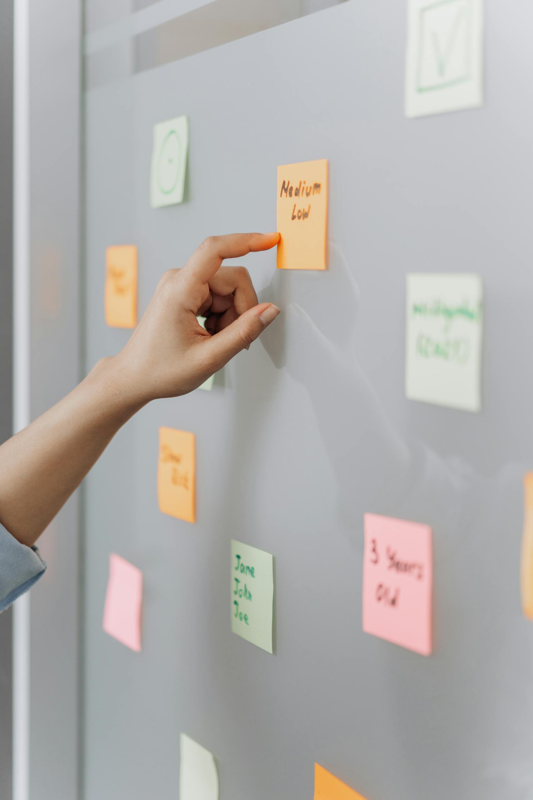 A Hand Pointing the Sticky Note on the Wall